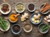 A flat-lay assortment of fresh medicinal kitchen herbs and spices on wood.