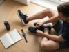 A man tying running shoes next to a daily habit tracker notebook.