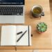 Flat lay workspace with notebook, herbal tea, and laptop for wellness blog ideas.